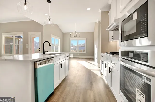 a large kitchen with stainless steel appliances granite countertop a stove a sink dishwasher and a refrigerator with wooden floor