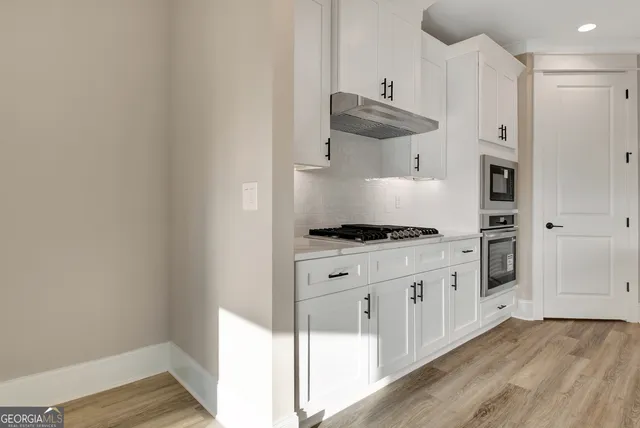 a large white kitchen with a sink a fireplace and cabinets