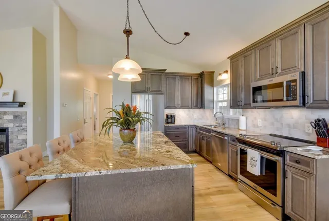 a kitchen with stainless steel appliances granite countertop a sink a stove top oven a counter space and cabinets