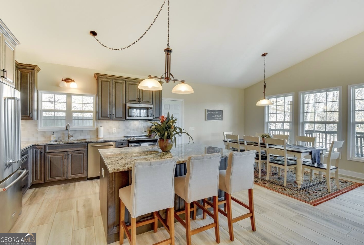 243 Degroff Lane Rabun Gap, GA 30568 - Photo 16 of 35 a kitchen with stainless steel appliances granite countertop a stove a sink a refrigerator a dining table and chairs with wooden floor