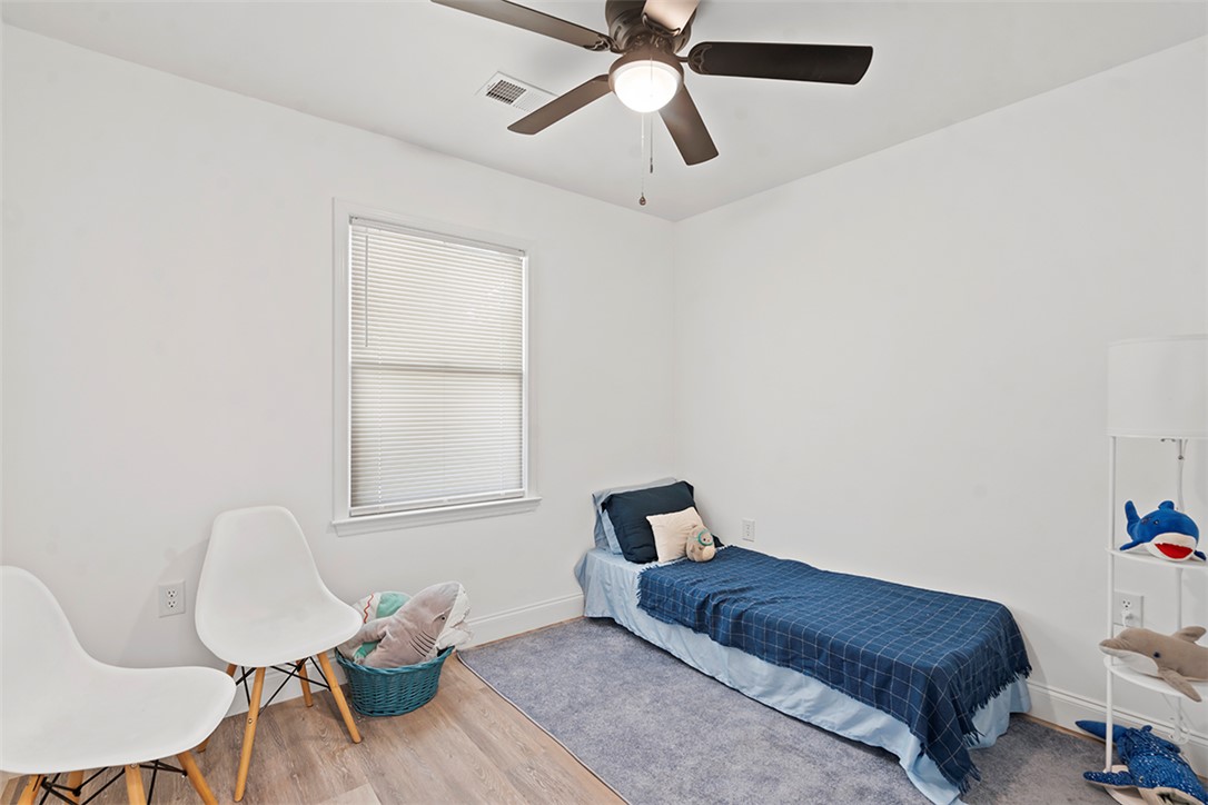 701 Quarry Street Anderson, SC 29624 - Photo 7 of 16 A well-lit bedroom features a window with blinds, light wood flooring, and a ceiling fan.