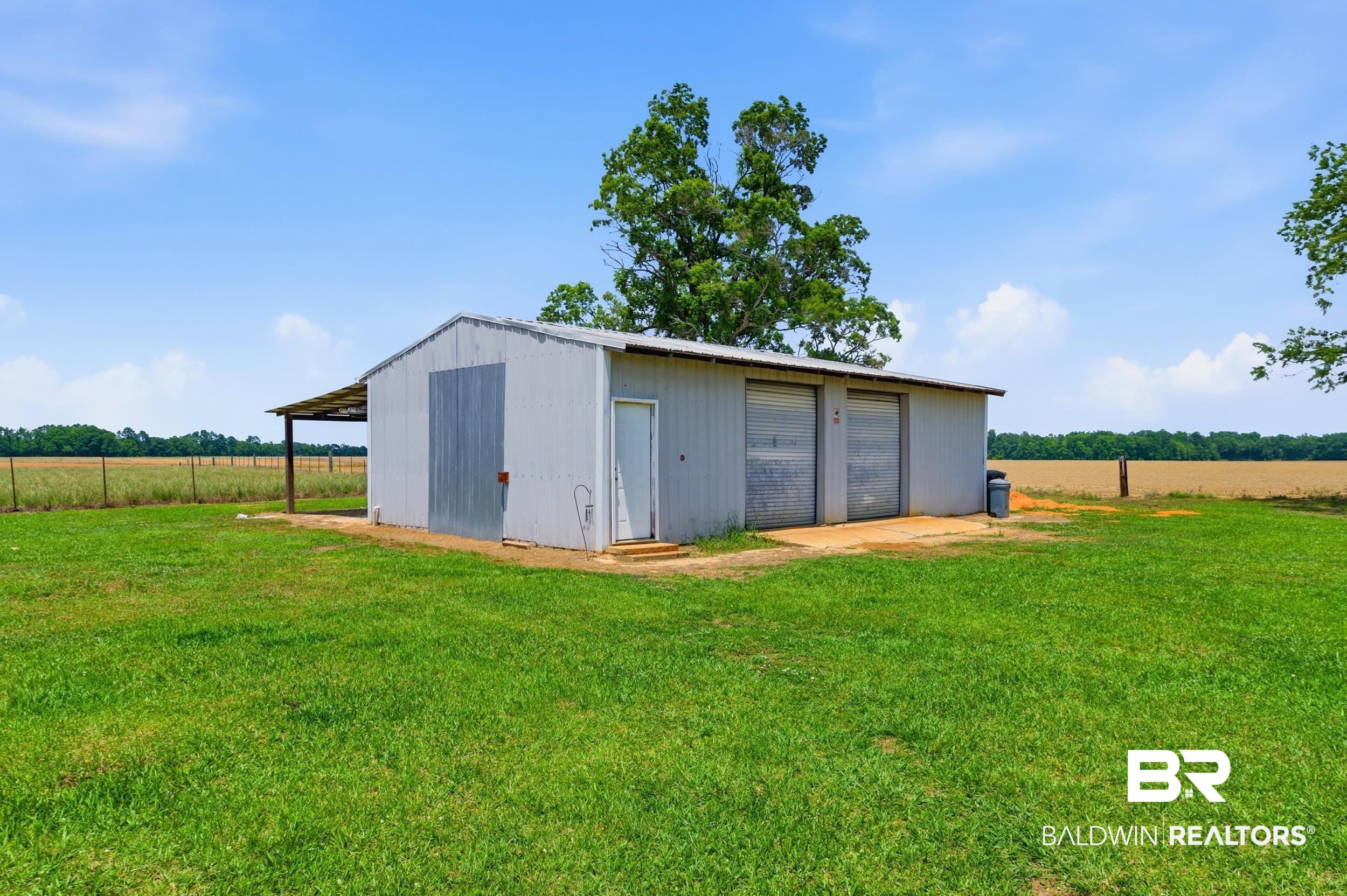 926 Tumbling Lane Atmore, AL 36502 - Photo 44 of 56 Metal outbuilding featuring a covered porch, an entry door, and two roll-up garage doors