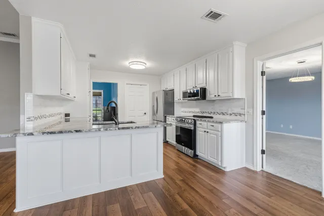 a kitchen with granite countertop white cabinets and white appliances