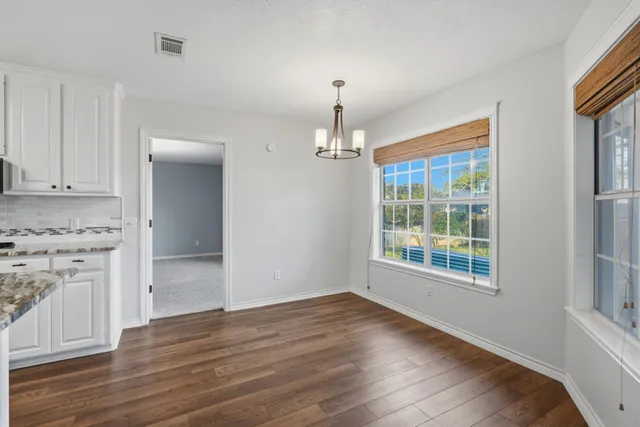 an empty room with wooden floor cabinet and windows