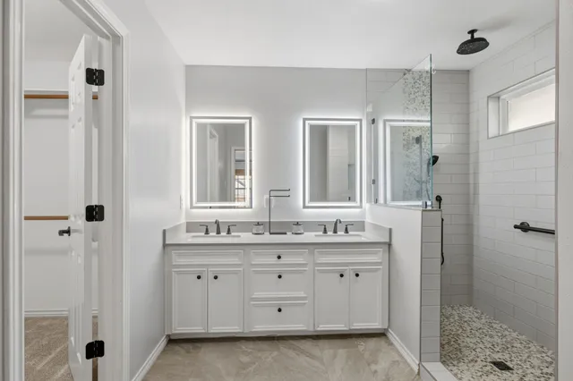 a bathroom with a double vanity sink a mirror and a shower