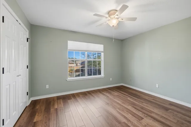 a view of an empty room with a window and wooden floor