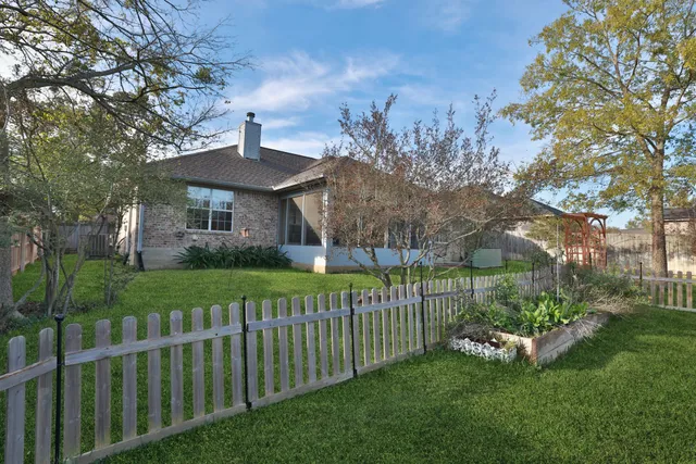a view of a house with a small yard and a large tree