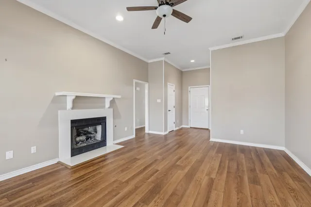 a view of an empty room with wooden floor fireplace and a window