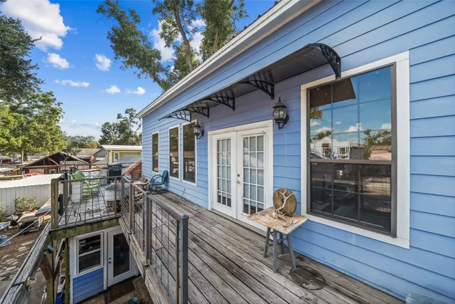 a view of a roof deck with table and chairs a barbeque with wooden floor and fence