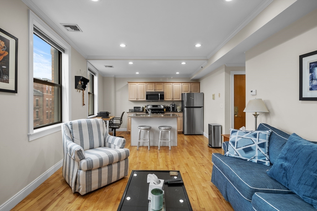 a living room with furniture kitchen view and a window
