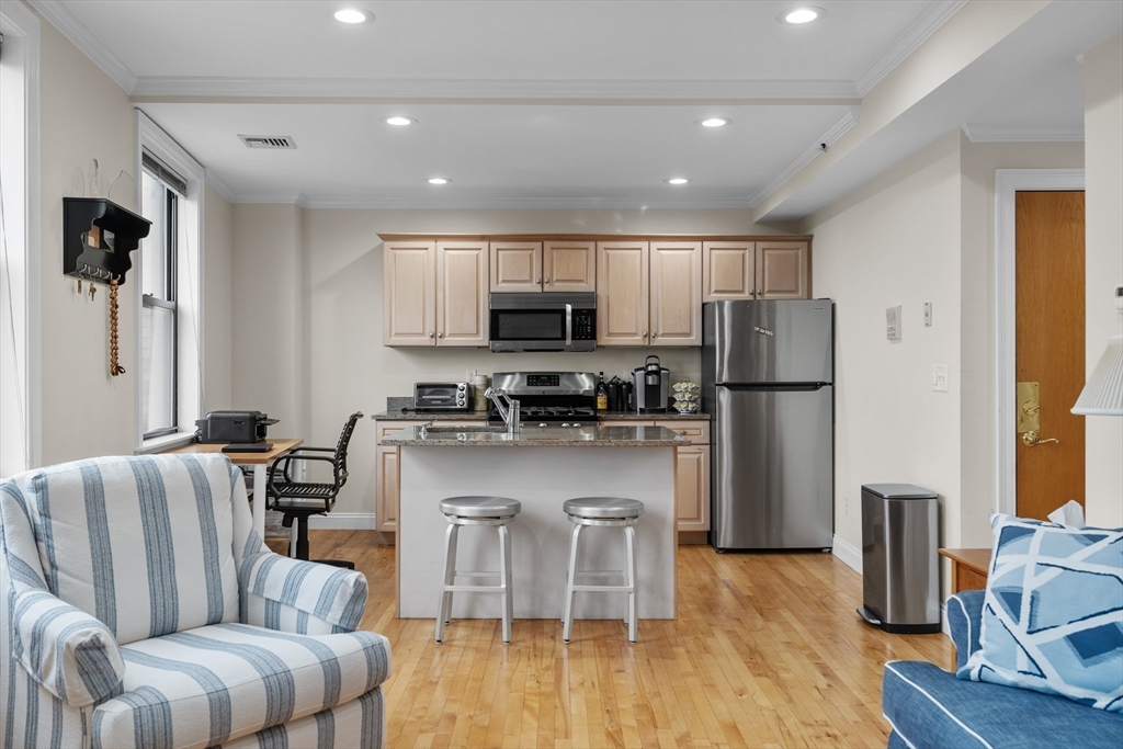 454 Hanover Street, Unit 5 Boston, MA 02113 - Photo 4 of 19 a living room with stainless steel appliances granite countertop couches a fireplace a flat screen tv and a refrigerator