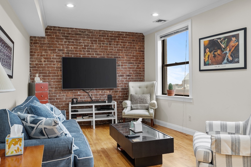 454 Hanover Street, Unit 5 Boston, MA 02113 - Photo 7 of 19 a living room with furniture a flat screen tv and kitchen view