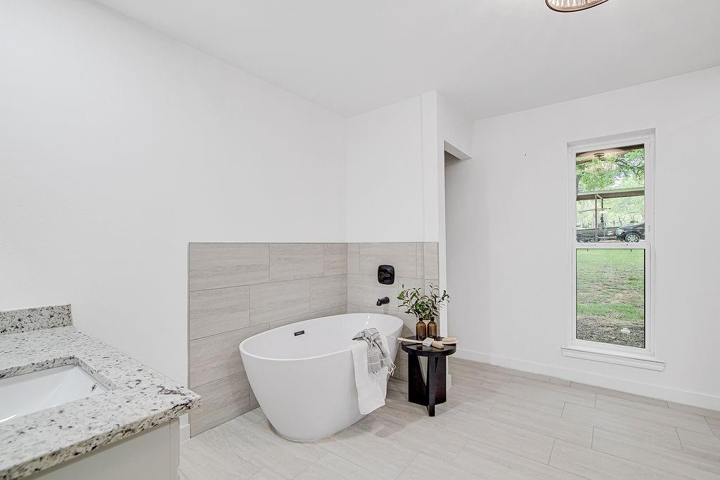 715 Pheasant Run Burleson, TX 76028 - Photo 15 of 28 a bathroom with a bathtub and a window