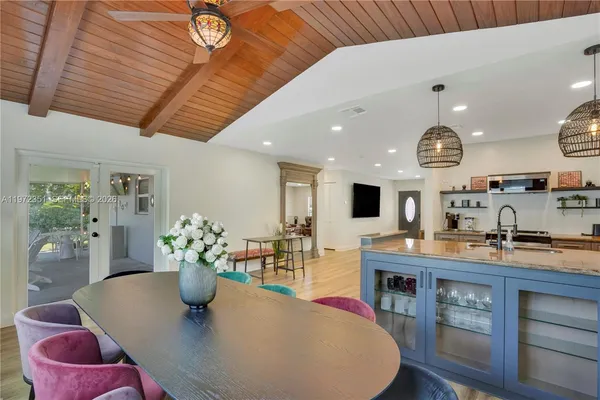 a kitchen with stainless steel appliances kitchen island granite countertop a stove a sink dishwasher and a dining table with wooden floor