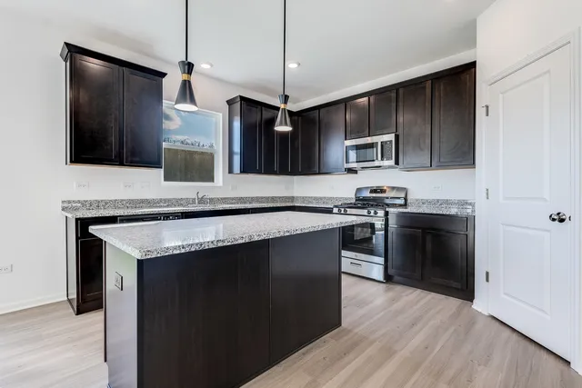 a kitchen with stainless steel appliances kitchen island granite countertop a stove a sink and a microwave