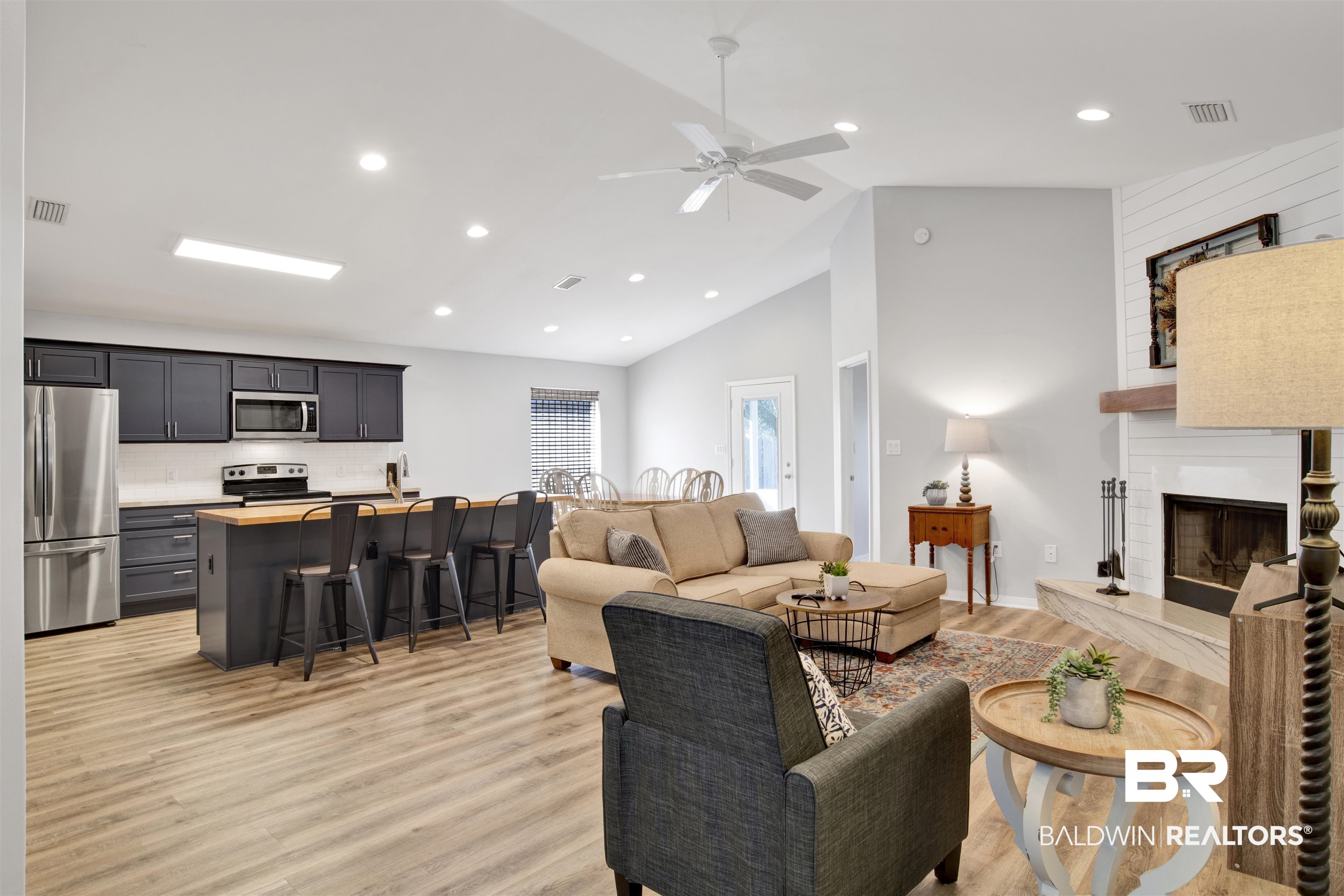 7145 Raintree Lane Gulf Shores, AL 36542 - Photo 4 of 25 Living room with ceiling fan, a fireplace, high vaulted ceiling, and light hardwood / wood-style flooring