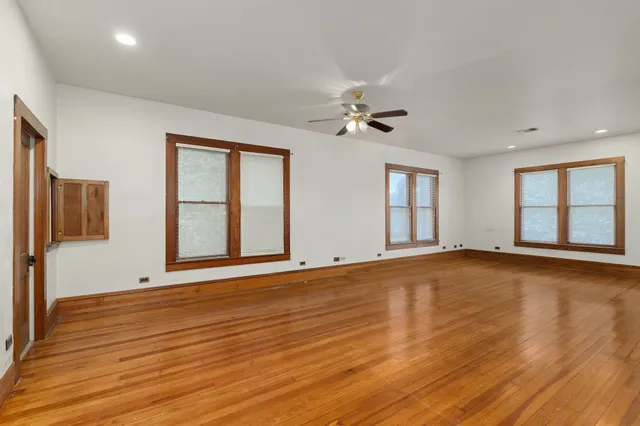 a view of an empty room with glass door and wooden floor