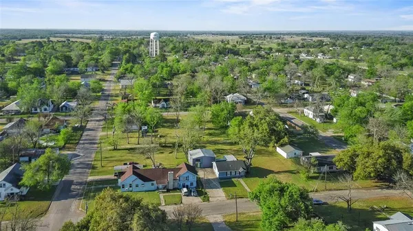 an aerial view of residential house with outdoor space and trees all around