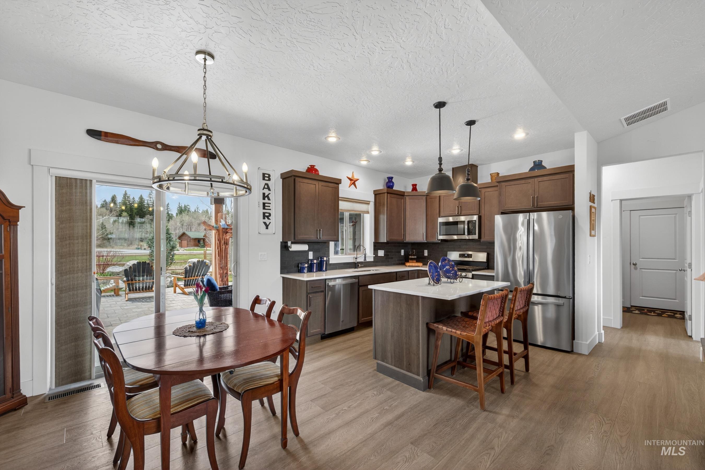1126 Mo's Way McCall, ID 83638 - Photo 18 of 50 Open-concept kitchen and dining area featuring wood-finish flooring, recessed lighting, and a kitchen island with seating
