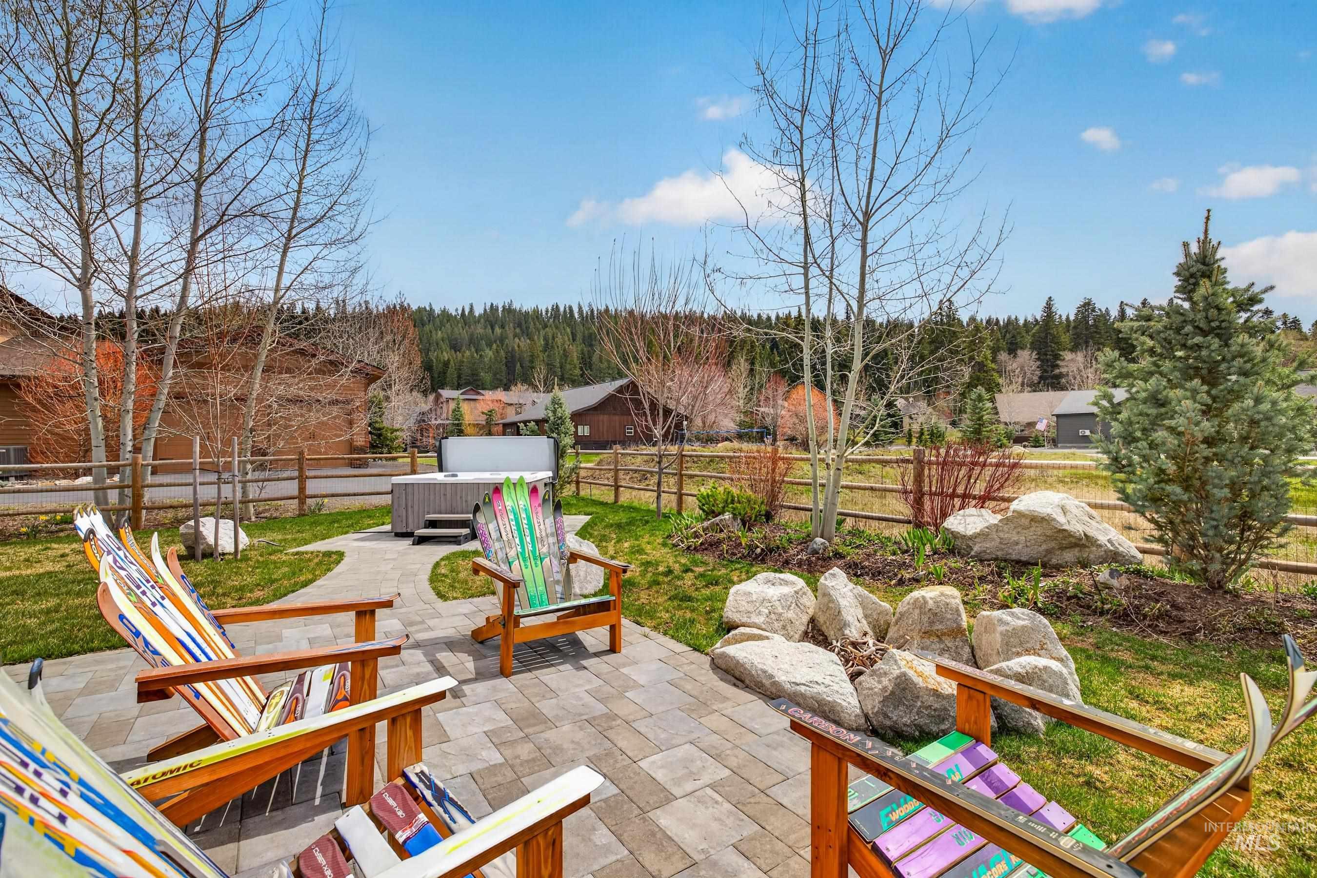 1126 Mo's Way McCall, ID 83638 - Photo 38 of 50 Outdoor paver patio featuring a built-in hot tub, a fire pit area with natural boulders, and a landscaped yard with mature trees