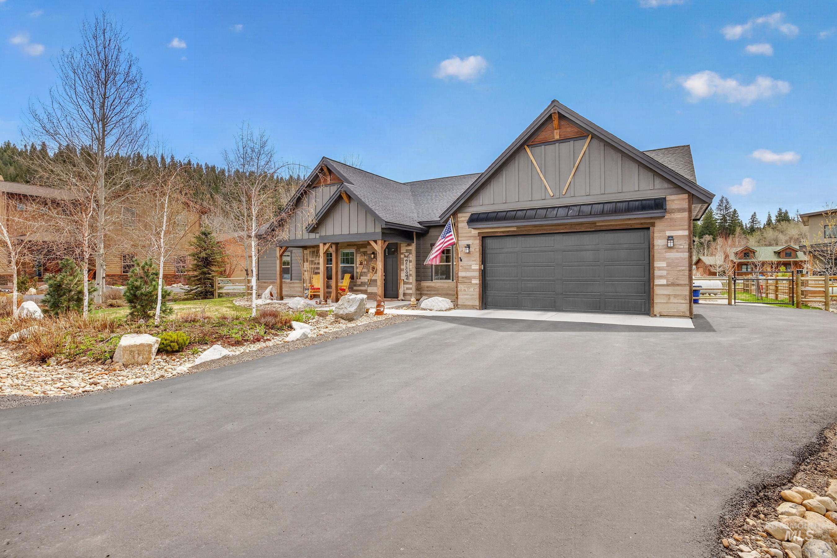 1126 Mo's Way McCall, ID 83638 - Photo 45 of 50 Craftsman-style exterior featuring stone accents, vertical siding, a covered porch, an attached garage, and a paved driveway