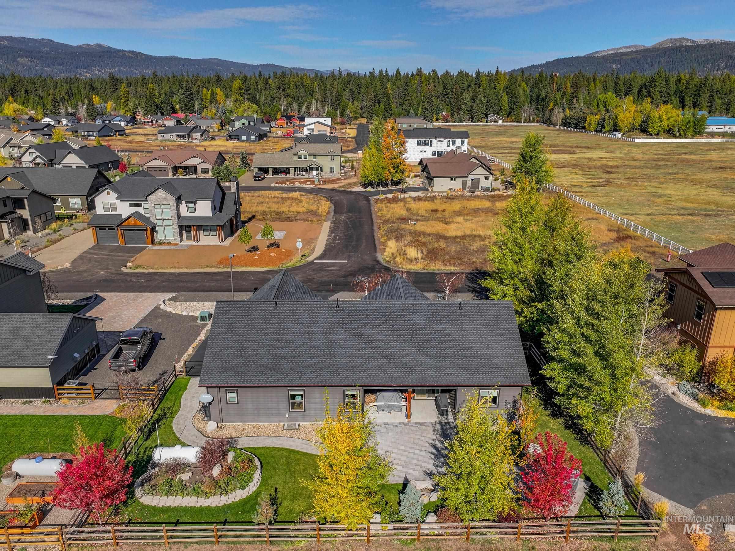 1126 Mo's Way McCall, ID 83638 - Photo 48 of 50 Rear exterior featuring a stone patio, fenced backyard, and mature landscaping with seasonal foliage
