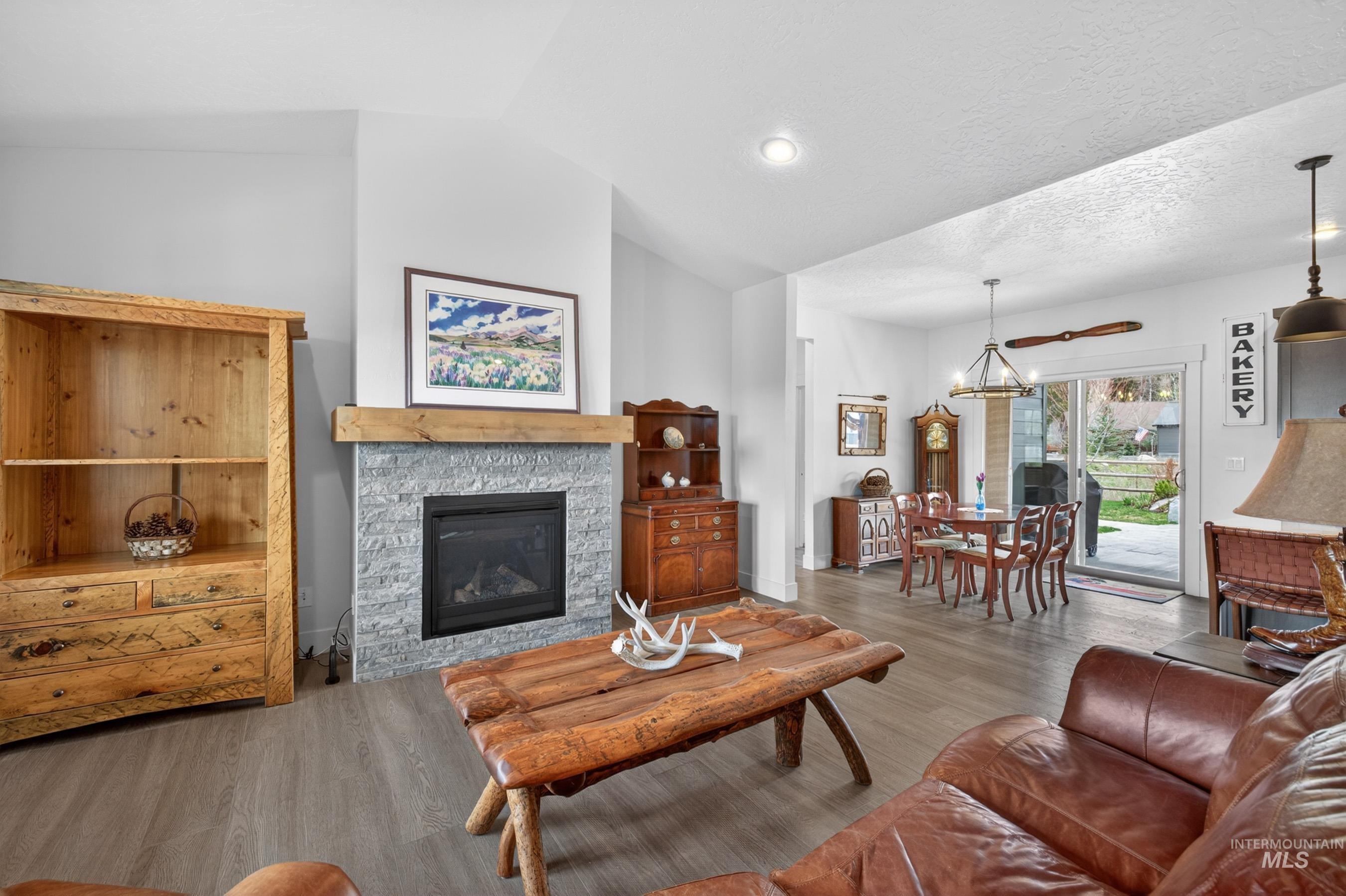 1126 Mo's Way McCall, ID 83638 - Photo 7 of 50 Living area featuring a stone-clad fireplace with a wood mantel, vaulted ceiling, and recessed lighting