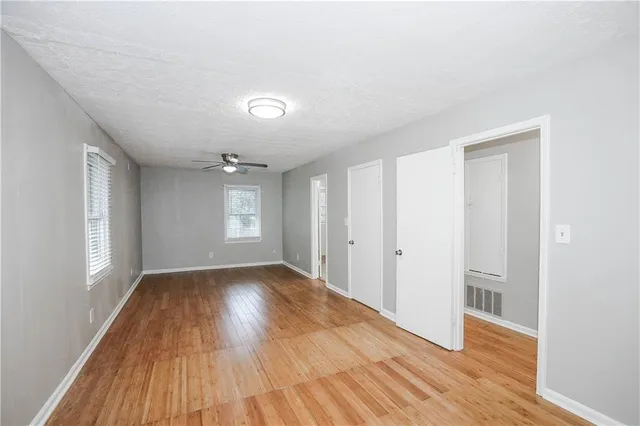 a view of an empty room with window and wooden floor