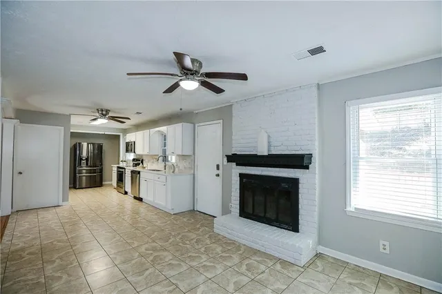 a view of a livingroom with a fireplace a ceiling fan and windows