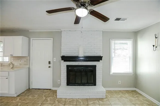 a living room with a fireplace furniture a ceiling fan and a window