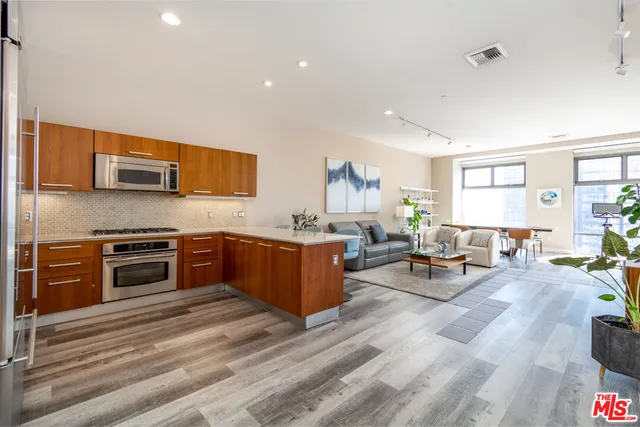 a large white kitchen with stainless steel appliances granite countertop a stove and a living room