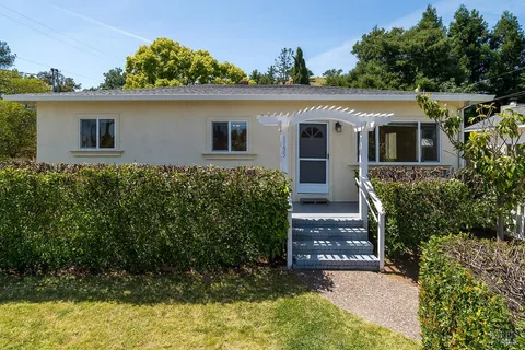 a view of a house with a small yard and potted plants