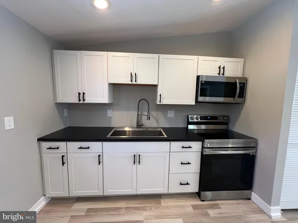 a kitchen with granite countertop white cabinets and black appliances
