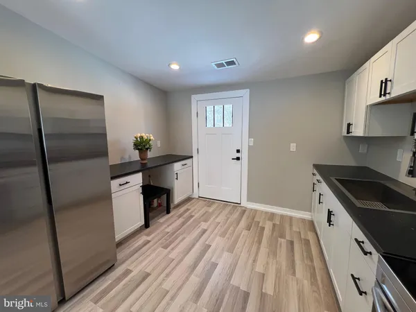 a kitchen with granite countertop a refrigerator a sink a stove and white cabinets