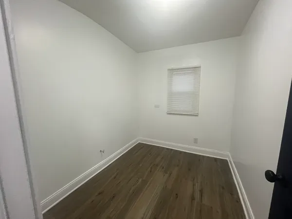 an empty room with wooden floor and white door