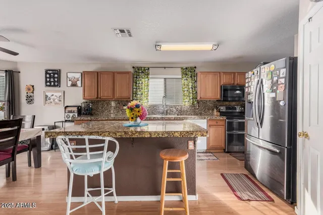 a kitchen with stainless steel appliances granite countertop a table chairs refrigerator and sink
