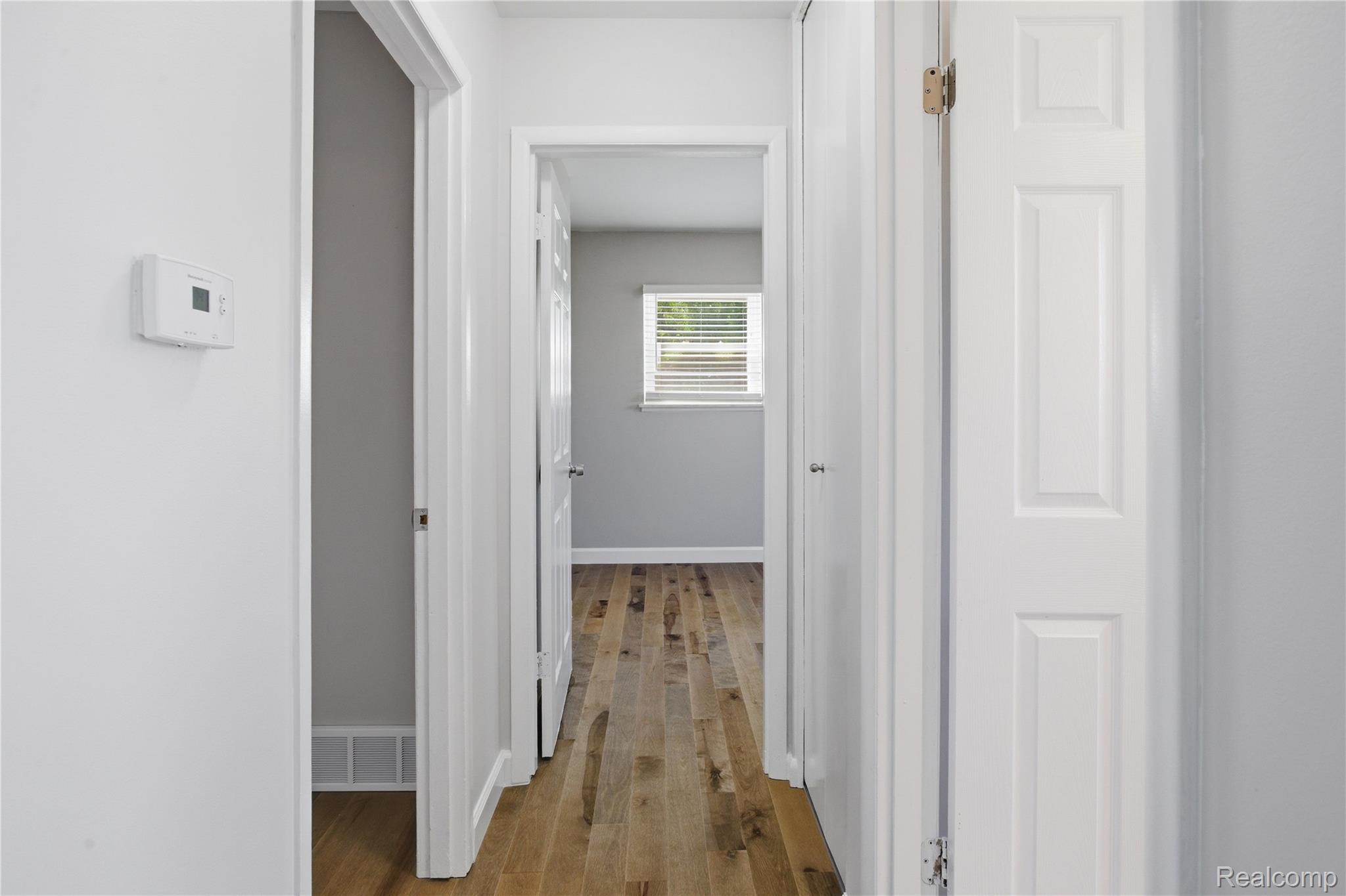 37257 Dundee Street Sterling Heights, MI 48310 - Photo 17 of 47 Long hallway with wood-finish flooring, white paneled doors, and light gray wall paint