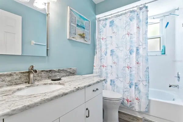 a bathroom with a granite countertop sink a toilet and a bathtub