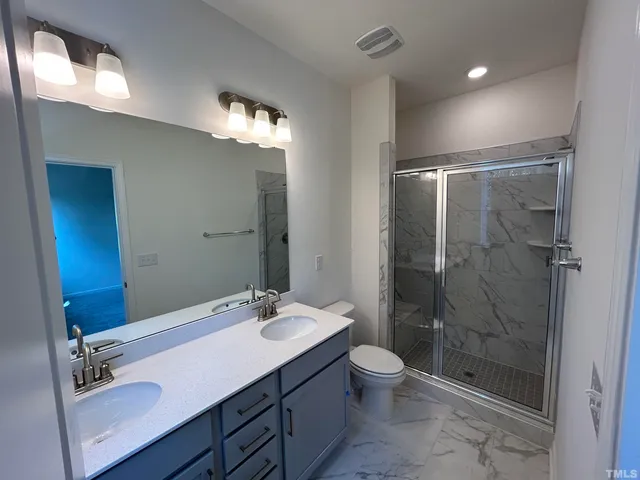 a bathroom with a double vanity sink toilet and shower
