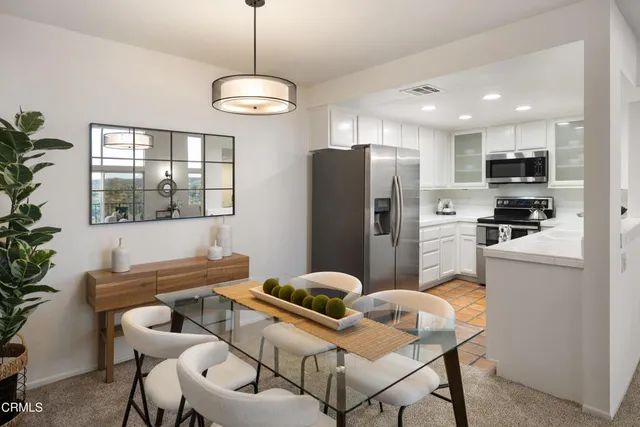 a kitchen with stainless steel appliances kitchen island granite countertop a refrigerator a stove a sink dishwasher a dining table and chairs with wooden floor