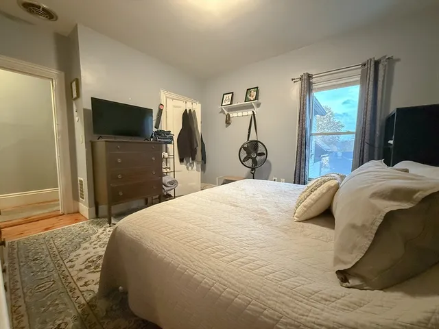 a bedroom with a bed and a flat tv screen on the dresser