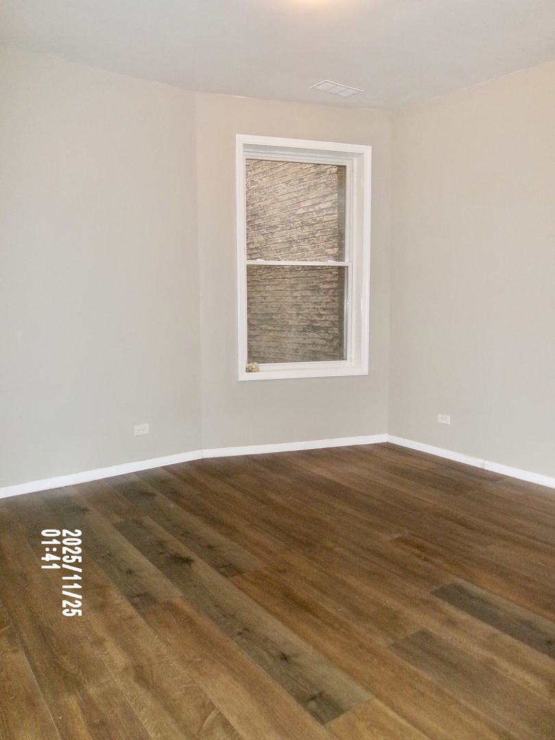 2852 East 91st Street, Unit 2 Chicago, IL 60617 - Photo 8 of 22 an empty room with wooden floor and windows