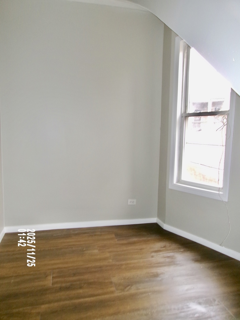 2852 East 91st Street, Unit 2 Chicago, IL 60617 - Photo 10 of 22 a view of an empty room with wooden floor and a window