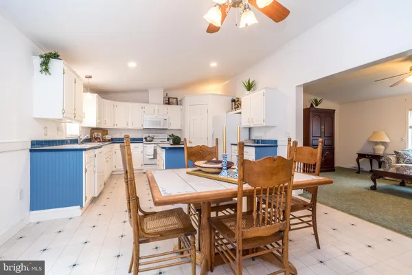 a view of a dining room and livingroom with furniture wooden floor a rug a flat screen tv a painting and a chandelier