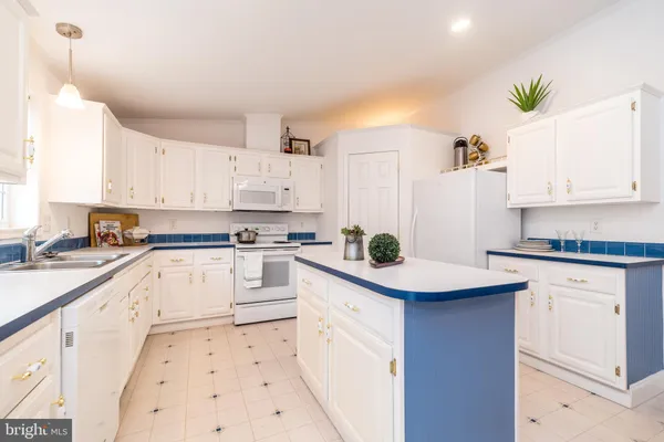 a kitchen with granite countertop white cabinets and white appliances