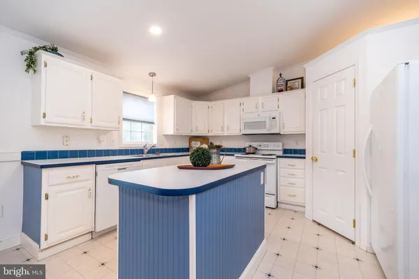 a kitchen with stainless steel appliances granite countertop a sink a stove a refrigerator and white cabinets