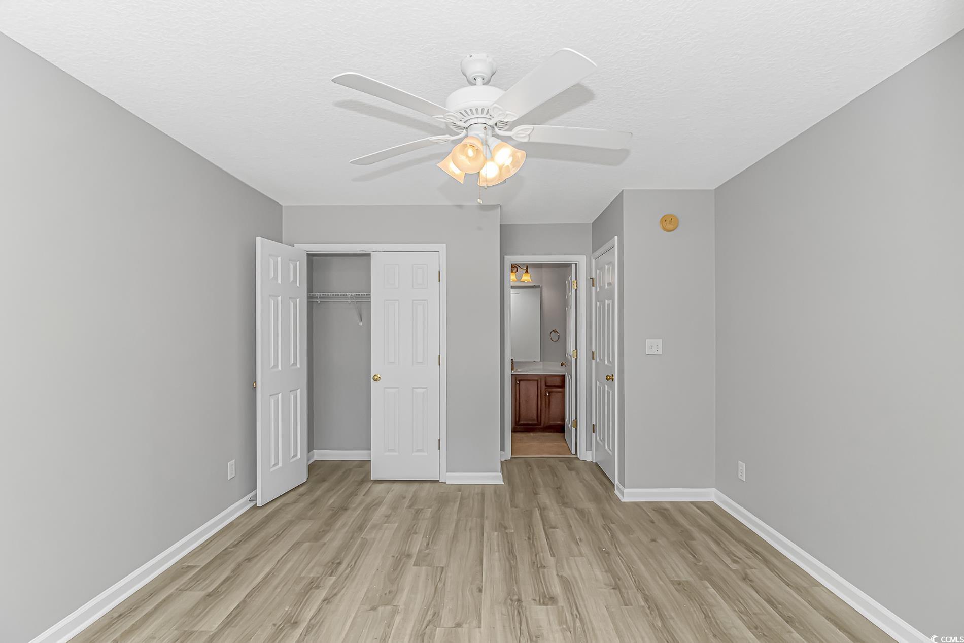 502 Lake Shore Drive Surfside Beach, SC 29575 - Photo 16 of 25 Unfurnished bedroom with a closet, light wood-style floors, ceiling fan, connected bathroom, and a textured ceiling
