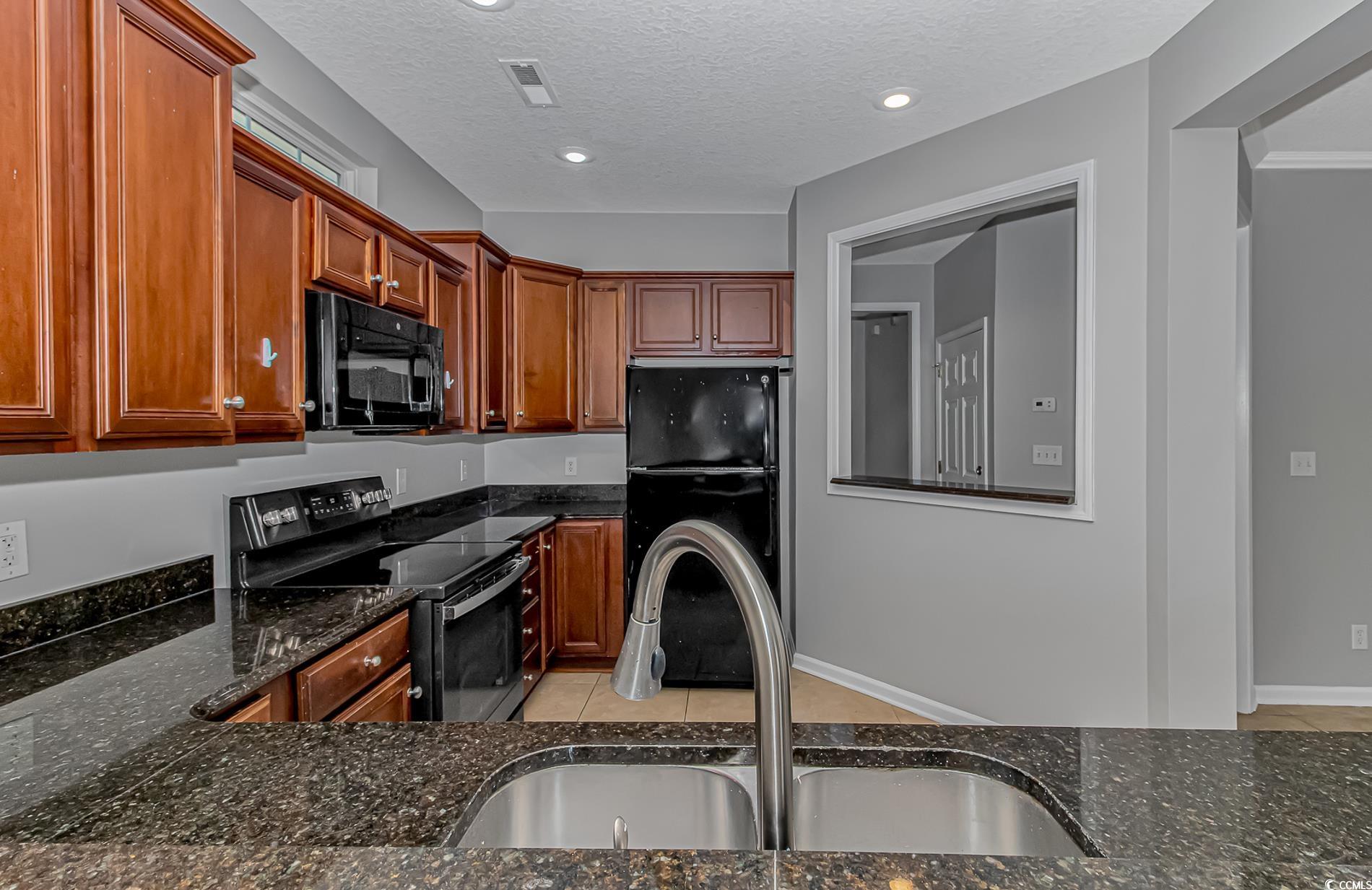 502 Lake Shore Drive Surfside Beach, SC 29575 - Photo 4 of 25 Kitchen with black appliances, a textured ceiling, dark stone counters, recessed lighting, and light tile patterned floors