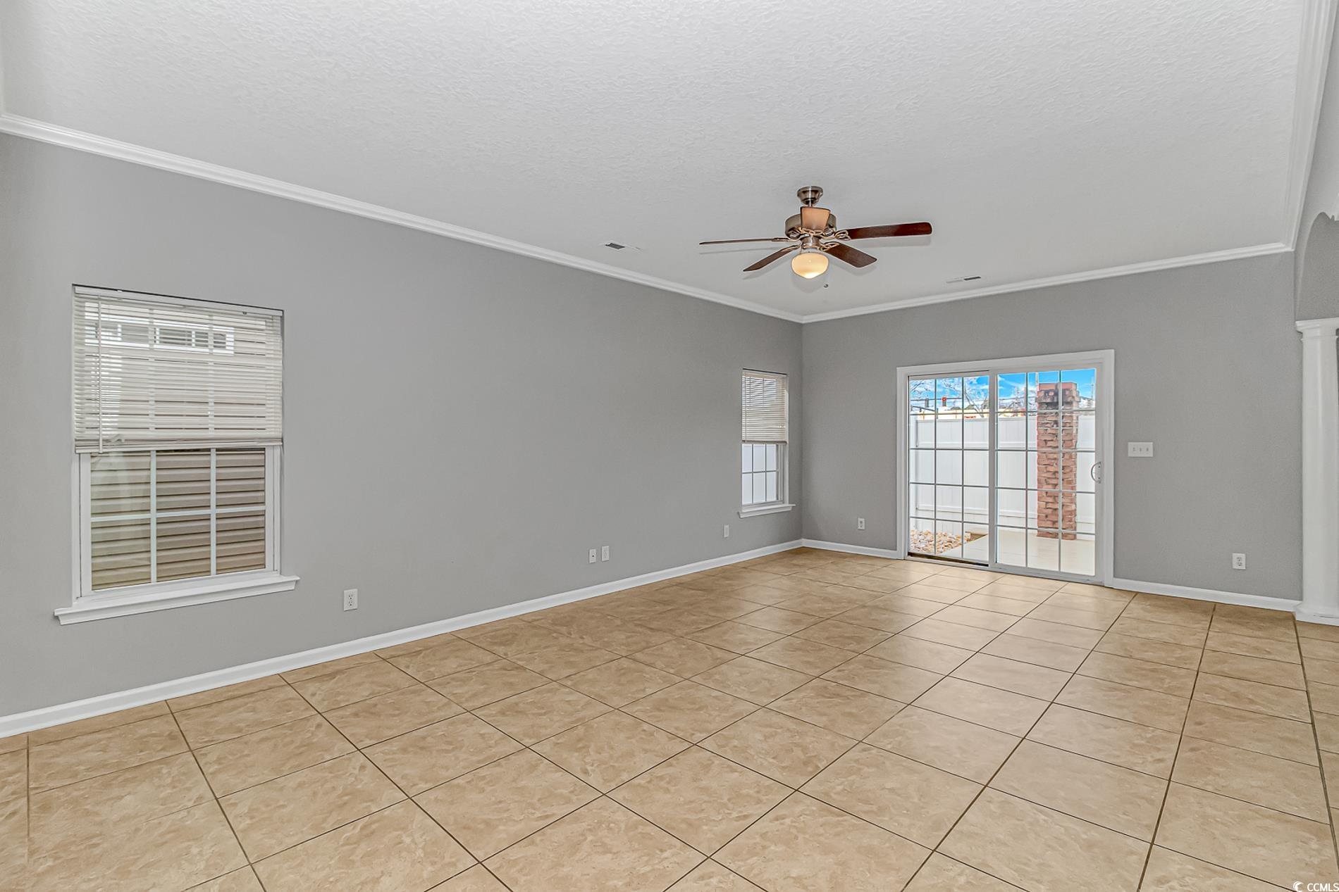 502 Lake Shore Drive Surfside Beach, SC 29575 - Photo 5 of 25 Unfurnished room with light tile patterned flooring, a textured ceiling, a ceiling fan, and ornamental molding
