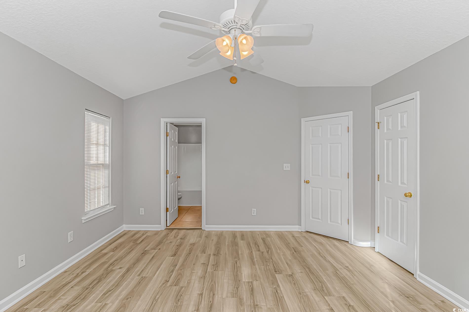 502 Lake Shore Drive Surfside Beach, SC 29575 - Photo 10 of 25 Unfurnished bedroom with lofted ceiling, light wood-type flooring, ceiling fan, connected bathroom, and a closet